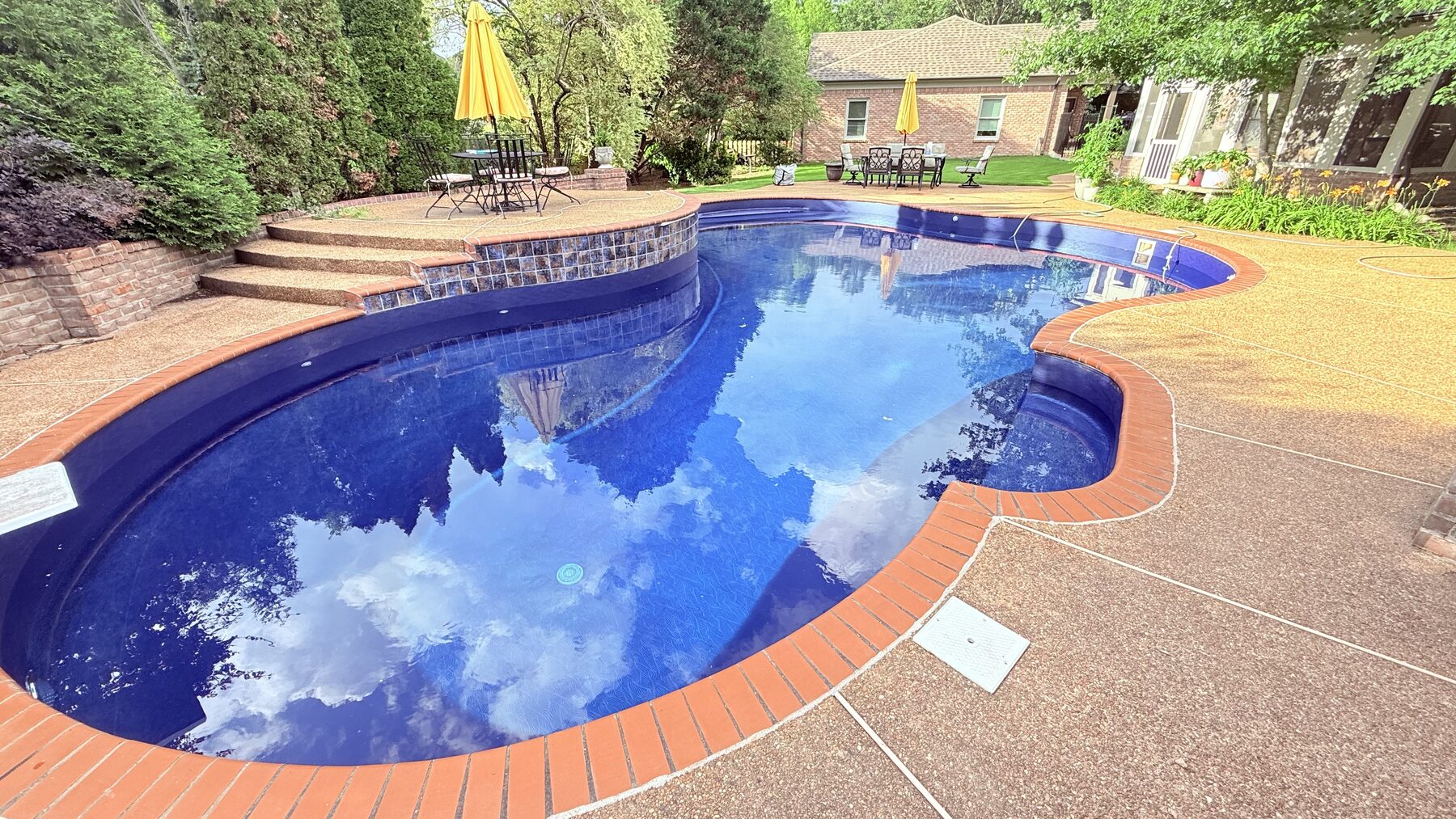 Freeform vinyl-lined pool filled with deep blue water, with a curved raised patio