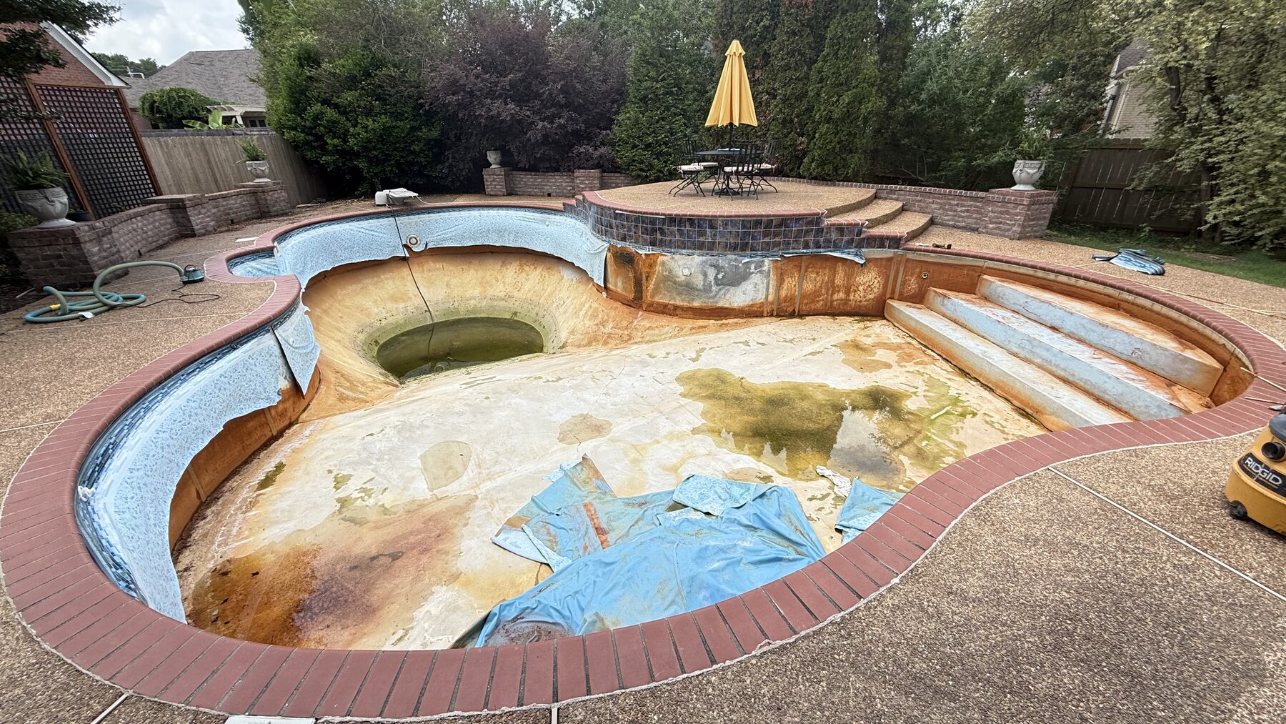 Curved pool with its old liner partly removed and the shell exposed